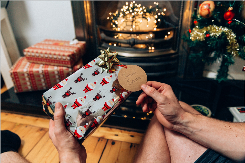 Gift wrapped in reindeer and Santa Claus wrapping paper, with a label 'Secret Santa' on it.